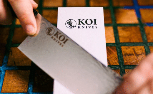 Hands sharpening a KOI knife on a whetstone during a demonstration.