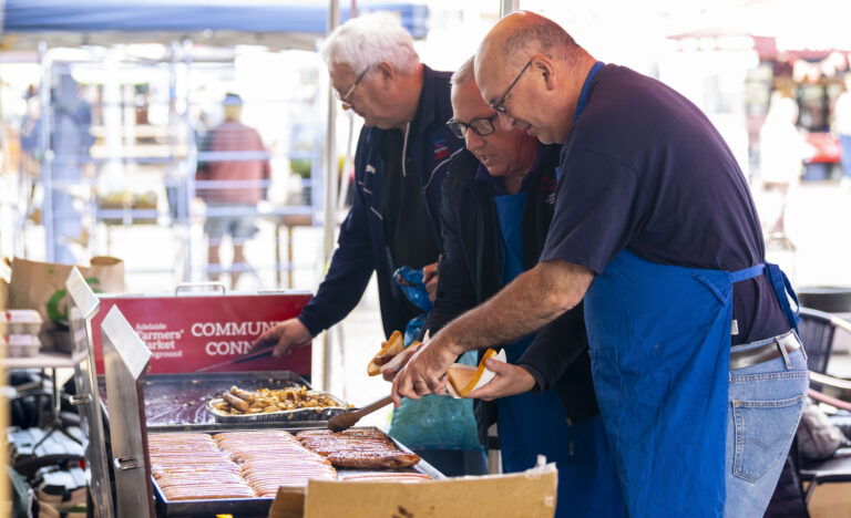 Members of Rotary Adelaide Central cooking sausages at the Adelaide Showground Farmers’ Market Community Connect BBQ.