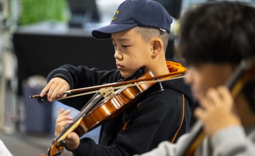 A young violinist from The Core Four Quartet plays with focus during a live performance at the Adelaide Showground Farmers’ Market.