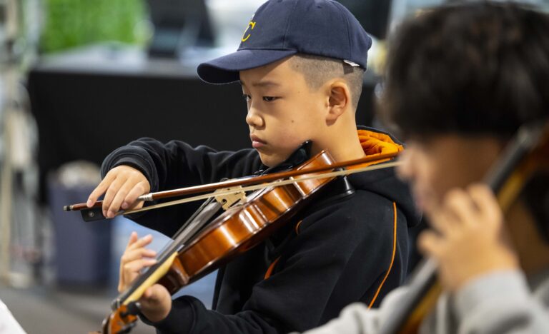 A young violinist from The Core Four Quartet plays with focus during a live performance at the Adelaide Showground Farmers’ Market.