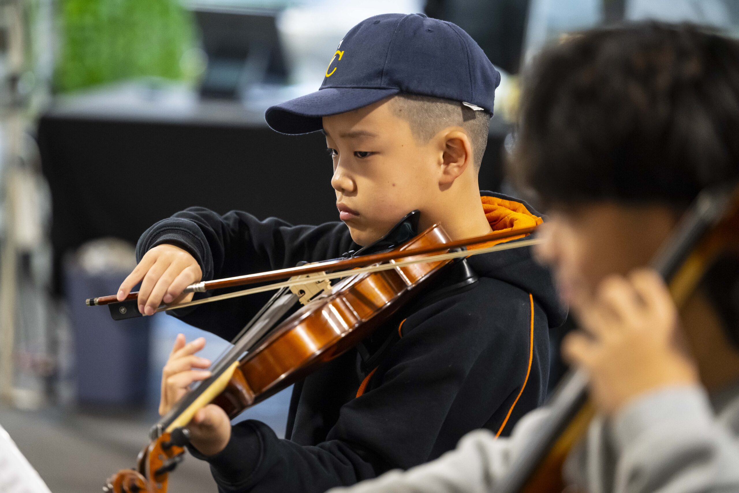 A young violinist from The Core Four Quartet plays with focus during a live performance at the Adelaide Showground Farmers’ Market.