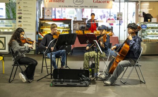 The Core Four string quartet performing live inside the Adelaide Showground Farmers’ Market, playing violins and cello among the market stalls