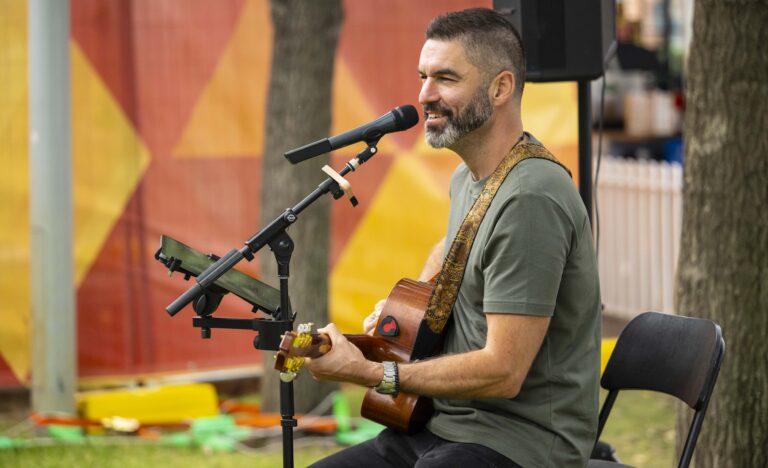 Busker Adam Moffatt performs live with acoustic guitar and vocals outdoors at the Adelaide Showground Farmers’ Market.