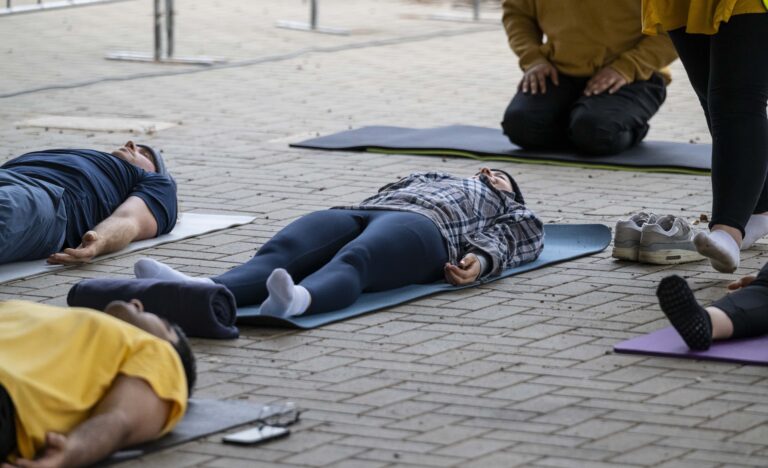 People relaxing on yoga mats during a community yoga and meditation session under the verandah at the Adelaide Showground Farmers’ Market before opening time.