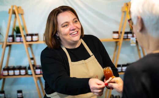 A Fiaje Jams stallholder offers a sample of handmade South Australian jam to a market visitor at the Adelaide Showground Farmers' Market.