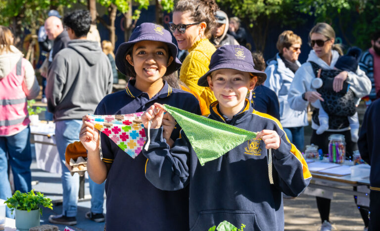 Two Goodwood Primary School students display colourful handmade fabric bunting at the Children’s Market.