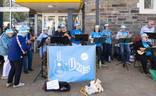 The Ukes performing with ukuleles and singing together outdoors at Goodwood Primary School.