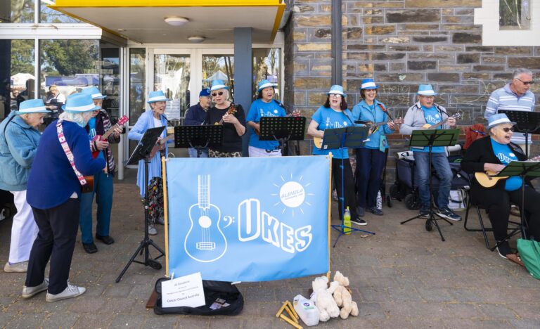 The Ukes performing with ukuleles and singing together outdoors at Goodwood Primary School.