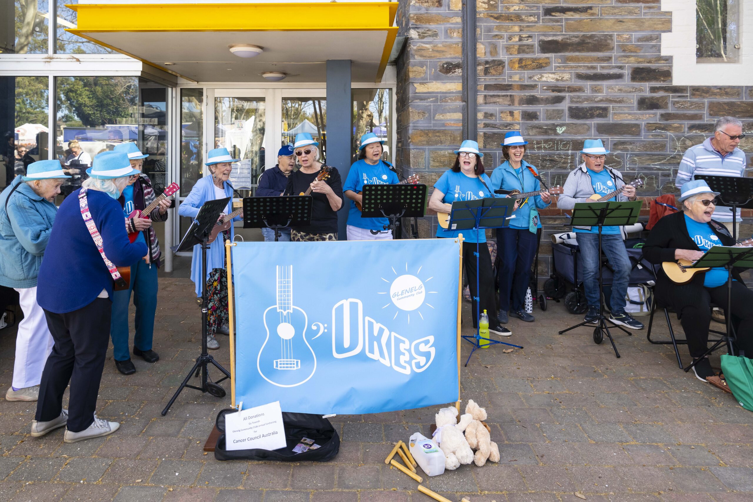 The Ukes performing with ukuleles and singing together outdoors at Goodwood Primary School.